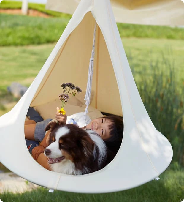 Child playing with a dog in a tent outdoors